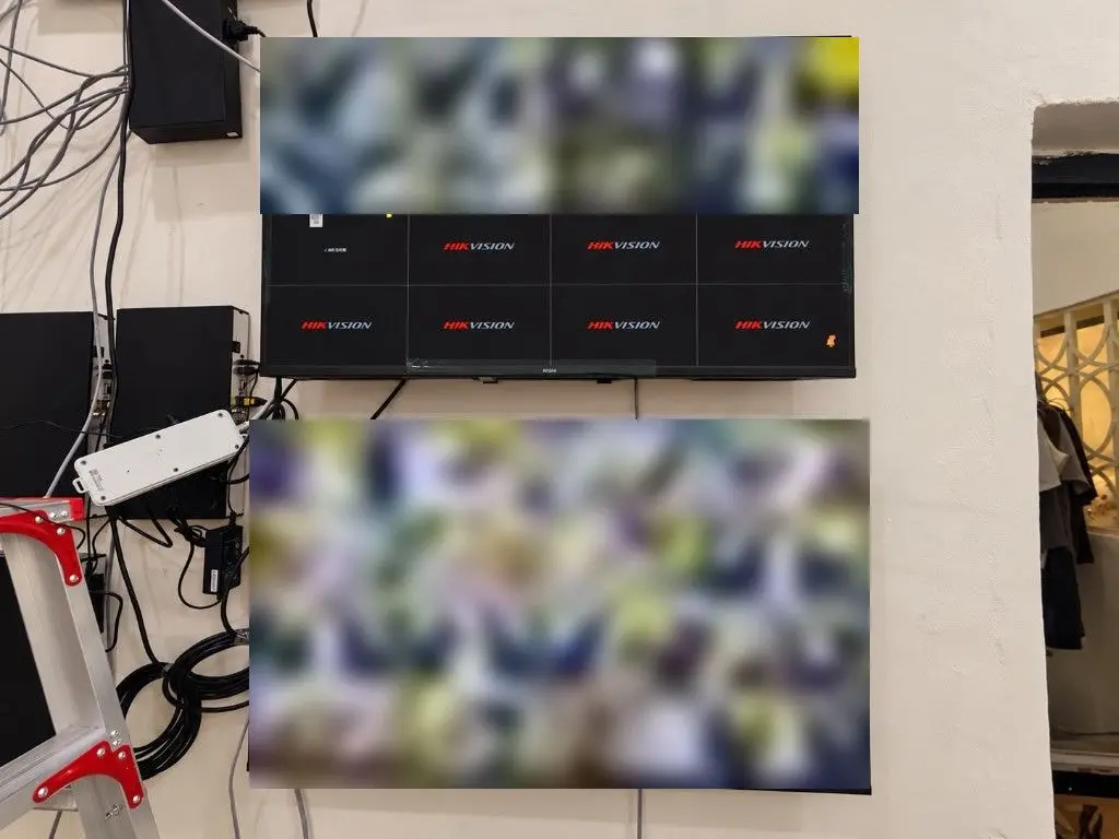 Finished control room with two wall-mounted monitors showing camera views and a stack of recorders. Screens are blurred.